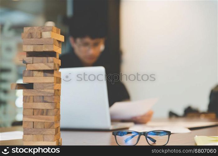 wood blocks stack game with background of businessman working in office - blur for background