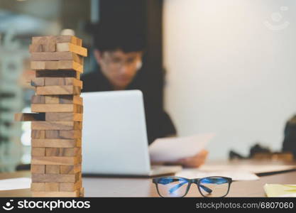 wood blocks stack game with background of businessman working in office - blur for background