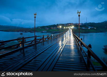 Wood bridge at night with river and mountain in Kanchanaburi Thailand