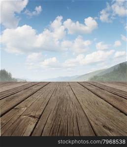Wood deck as a tranquil old rustic country patio floor in perspective with a summer sky on a beautiful mountain range with forest trees as a symbol of travel and backyard living.