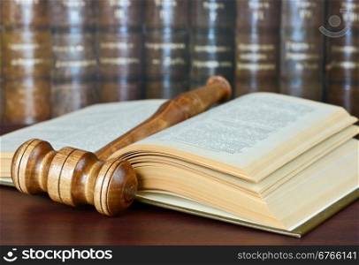 Wood gavel and old yellowed book on the background of shelves of old books