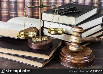 Wood gavel, bunch of keys, scales and stack of old books against the background of a row of antique books bound in leather
