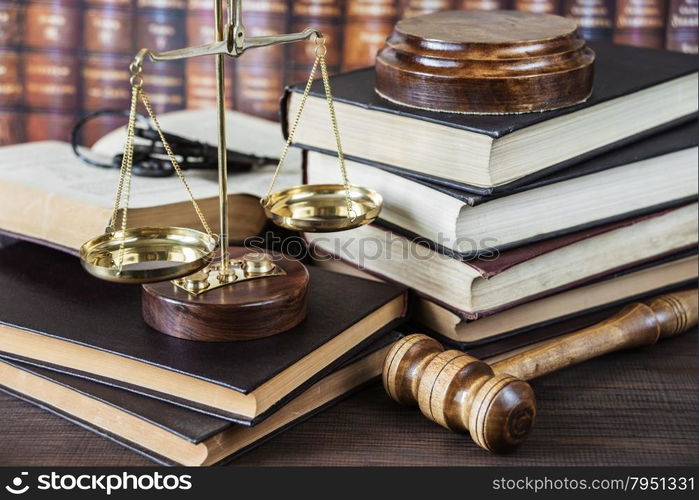 Wood gavel, bunch of keys, scales and stack of old books against the background of a row of antique books bound in leather