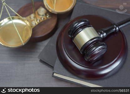 Wood gavel, soundblock, scales and stack of old books bound in leather on the wooden background