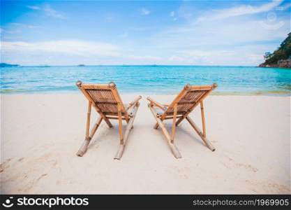 Wood lounge chairs on beautiful tropical beach. White lounge chairs on a beautiful tropical beach