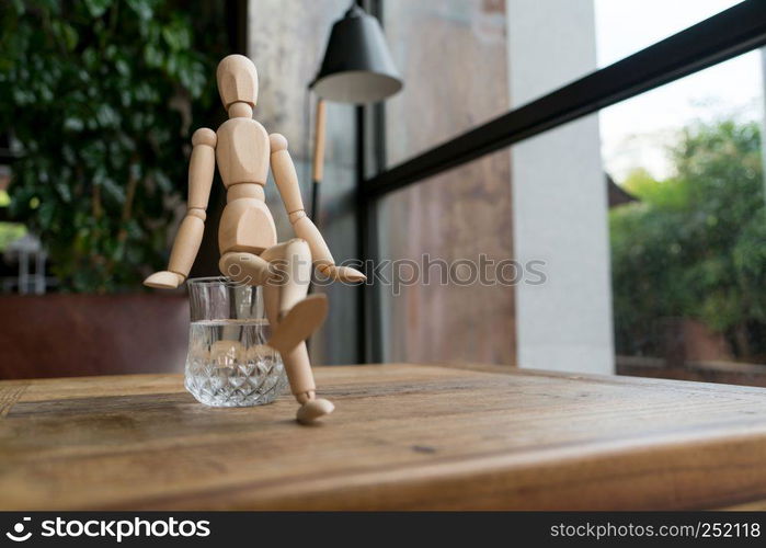 wood man is sitting on a glass of water