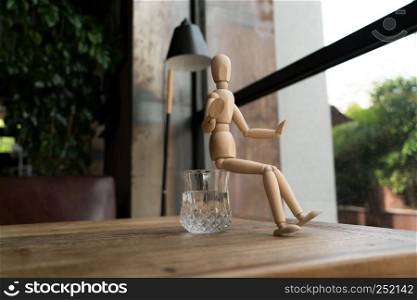 wood man is sitting on a glass of water