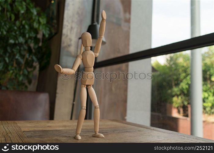 wood man is standing and raise the hand up