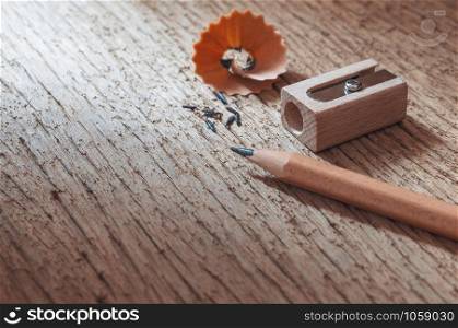 Wood pencil with sharpening shavings on old wooden texture background