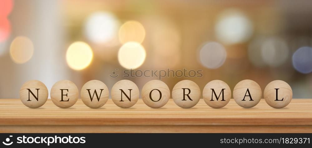 Wood sphere with NEW NORMAL word on wooden table over blur bokeh background.