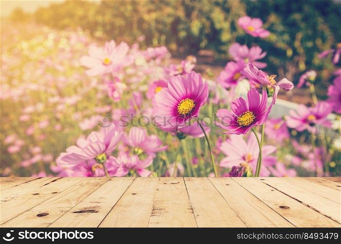 wood table and field cosmos with sunlight. vintage tone photo.