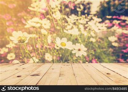 wood table and field cosmos with sunlight. vintage tone photo.