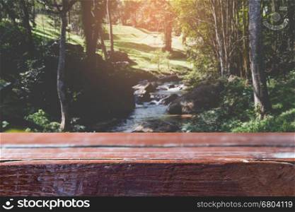 wood table for montage or display your product with blur background of water run through stone in creek stream in forest