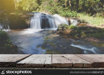 wood table for montage or display your product with blur background of waterfall cascade and creek stream in forest
