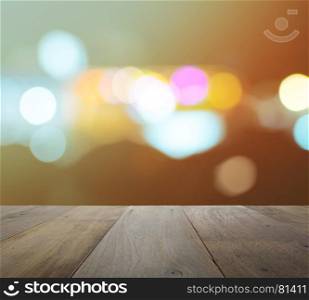 wood table top on abstract background with bokeh defocused lights and shadow from cityscape at night, vintage or retro color tone