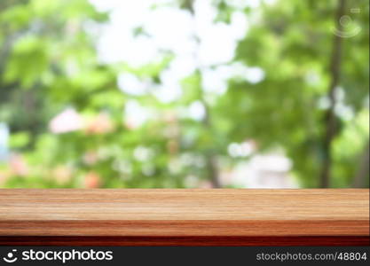 Wood table top on bokeh green leaves background, for display your products