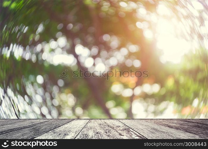 Wood table with blurred nature background. Abstract blurred tree with sunlight and wood shelf product display.Empty perspective wood table and space with green nature blur background.Vintage filtered.