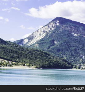 Wooded shore of the lake in French Alps. Lake Castillon is a reservoir in Alpes-de-Haute-Provence in France.