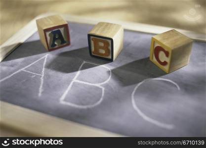 Wooden alphabet blocks on a chalkboard