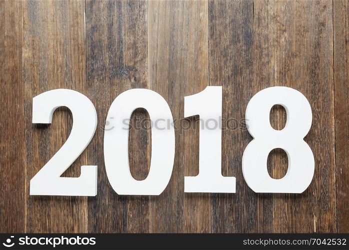 Wooden and painted with white color digits 2018 on rustic rough wooden background as concept of New Year and Christmas.Top view.