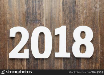 Wooden and painted with white color digits 2018 on rustic rough wooden background as concept of New Year and Christmas.Top view.