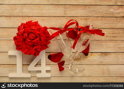Wooden background with glasses of champagne, flowers and wooden numbers of dated 14 February. The concept of Valentine Day and restaurant romantic dinner