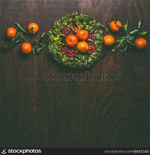 Wooden background with tangerines garland with leaves wreath , top view with copy space for your design