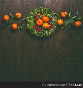 Wooden background with tangerines garland with leaves wreath , top view with copy space for your design