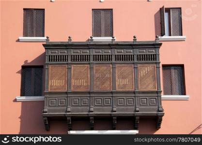 Wooden balcony, windows and pink wall of building in Trujillo, north Peru
