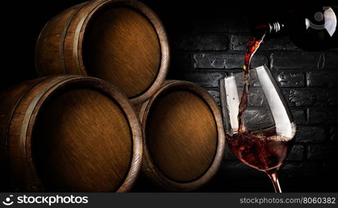 Wooden barrels and wine pouring into wineglass in cellar