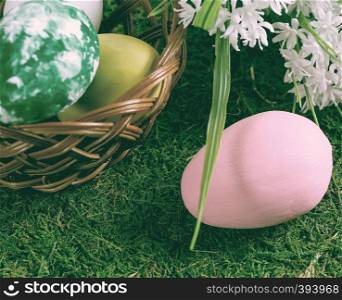 Wooden basket with Easter eggs on the grass field.
