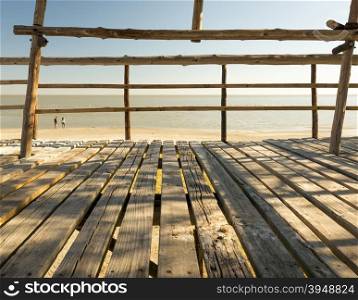 Wooden beach hut looks out over two tourists in the Makgadikgadi Pan in Botswana, Africa
