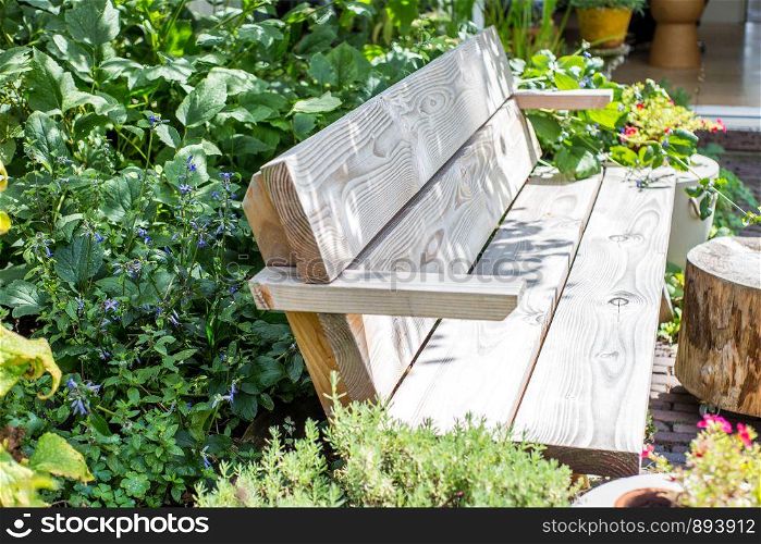 Wooden Bench in a wildflower garden. with green plants and colorful flowers with sunlight beauty. Wooden Bench in a wildflower garden. with green plants and colorful flowers with sunlight