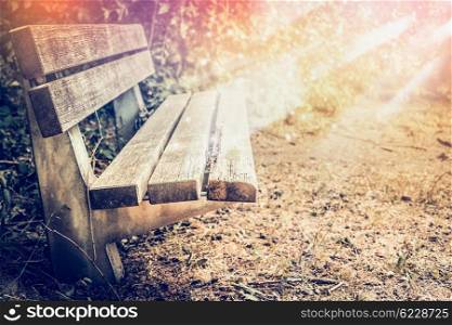 Wooden bench in the autumn park with sun rays. Outdoor Fall background with old bench.
