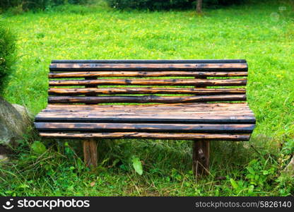 Wooden bench in the green park. Lawn with green grass