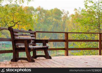 Wooden bench on a bridge over a lake in an autumn park