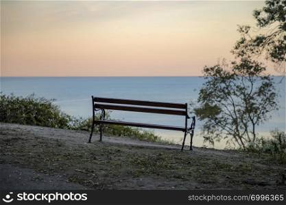 Wooden bench with a view at sea and day sky. Beautiful place for relaxing and enjoying nature. Traveling stop for travelers.