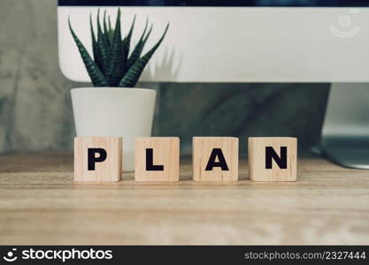 "Wooden block cube with alphabet text "PLAN" on wood table. education working information."