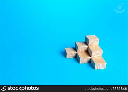 Wooden blocks pyramid on a blue background. Minimalism. Simple shapes geometry. Slide for presentation. Copy space, place for text. Steps.