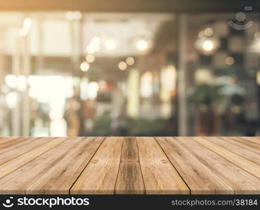 Wooden board empty table top on of blurred background. Perspective brown wood table over blur in coffee shop background - can be used mock up for montage products display or design key visual layout.