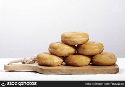wooden board with doughnuts stacked on top of each other forming a pyramid on a white background