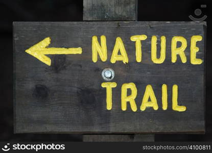 Wooden board with Nature Trail sign painted yellow.