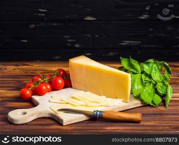 wooden board with parmesan cheese, fresh cherry tomatoes, lettuce, sea salt and red pepper. The knife for cutting vegetables. Appetizing still life from vegetables. wooden board with parmesan cheese, fresh cherry tomatoes, and green basil. The knife for cutting vegetables. Appetizing still life from vegetables