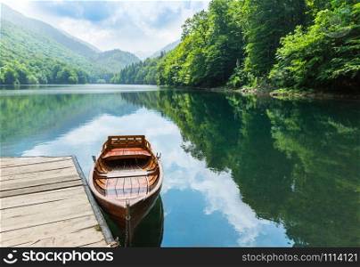 Wooden boat at pier on mountain lake. Biograd lake, Montenegro