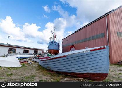 Wooden boat on land with a large ship in the background at the docks