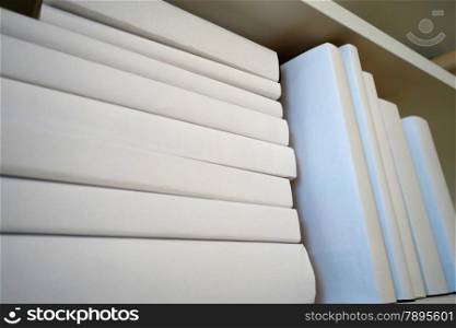 Wooden book shelf with white books in the room. Shelf with white books