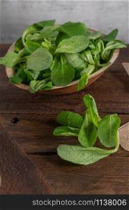 Wooden bowl with corn salad leaves, vertical shot