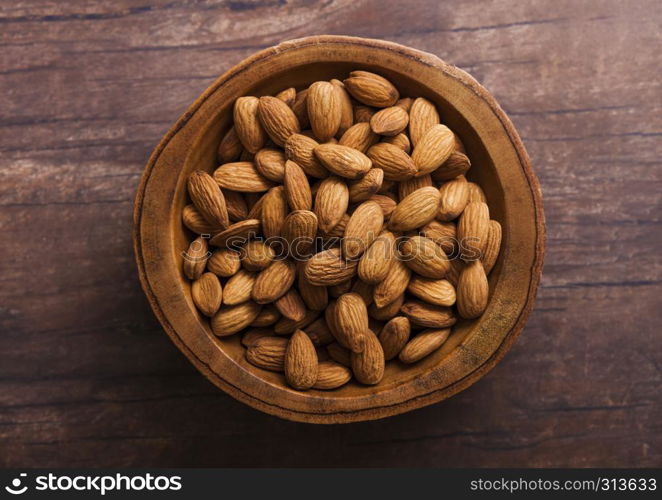 Wooden bowl with fresh raw almond nuts on wooden background