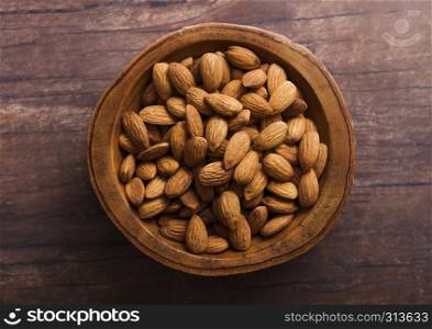 Wooden bowl with fresh raw almond nuts on wooden background