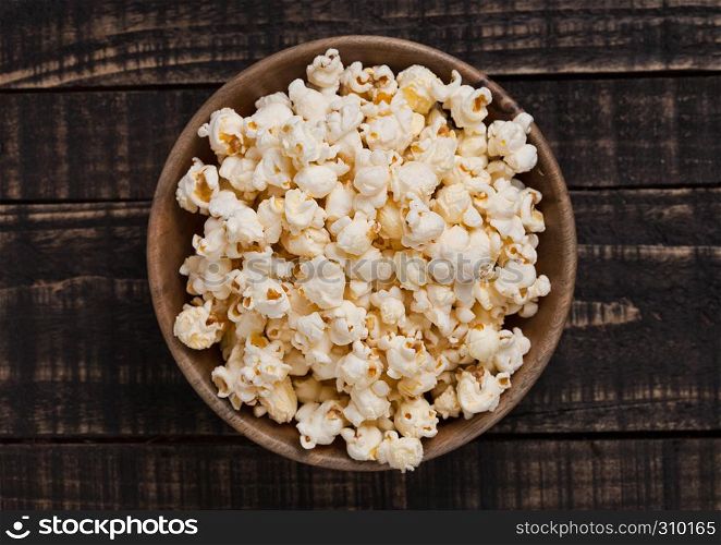 Wooden bowl with fresh salted popcorn on wooden background